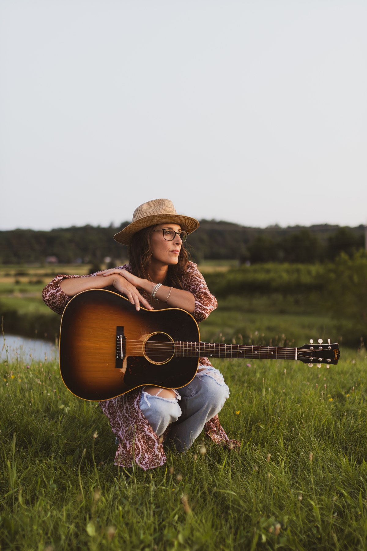 Michelle Hedley with her acoustic guitar in a sunlit field