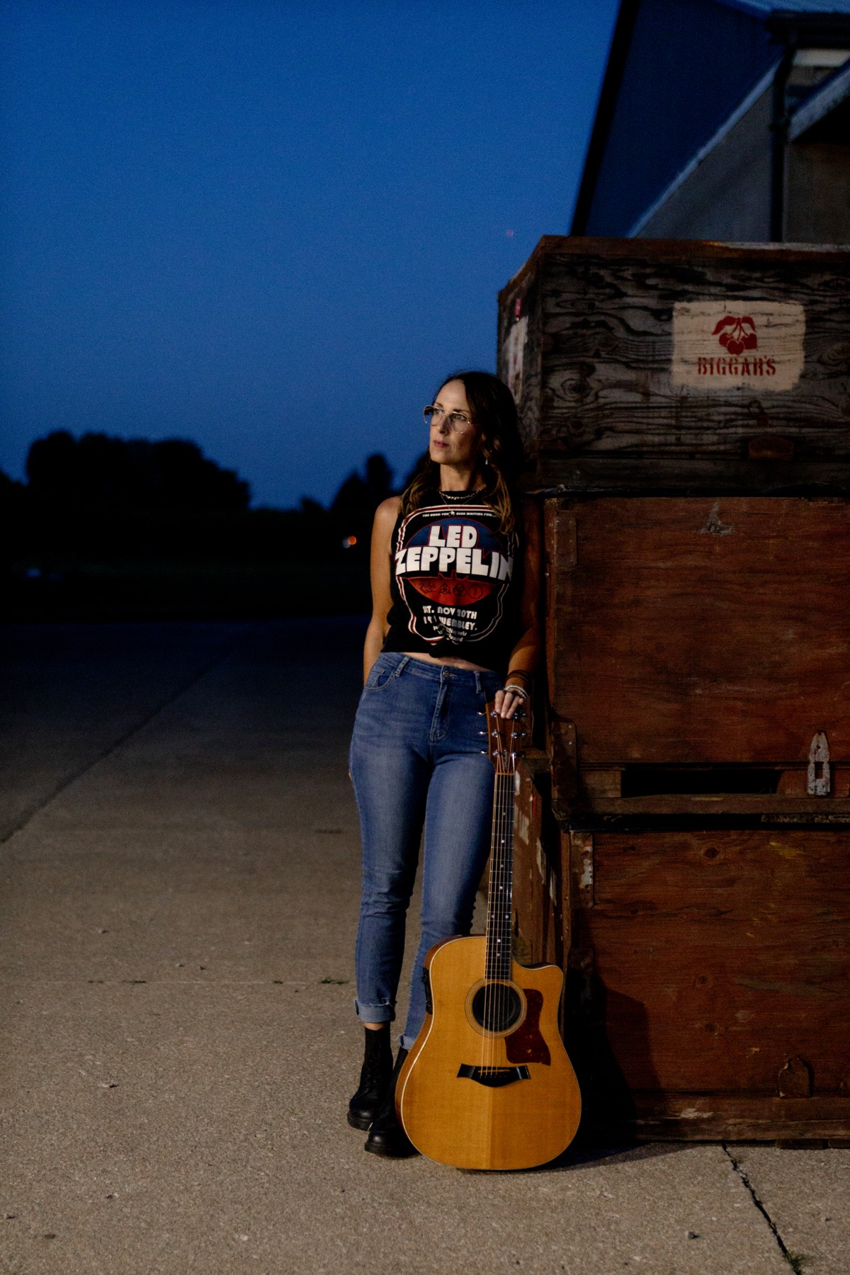 Michelle Hedley in a Led Zeppelin shirt standing beside her acoustic guitar